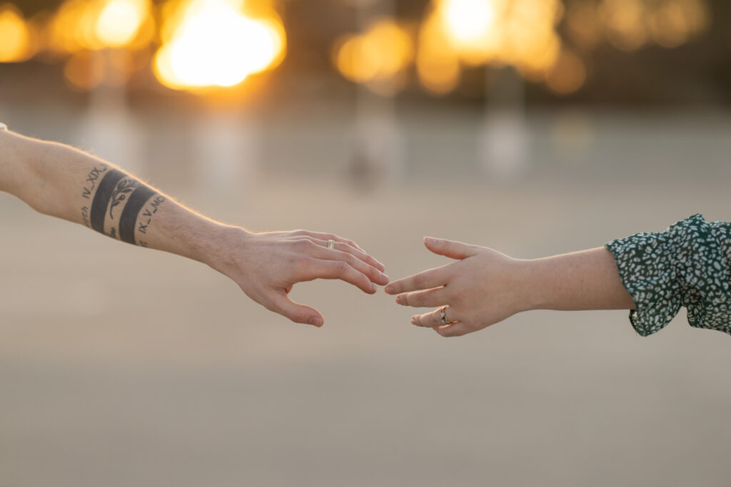 hands almost touching at sunset