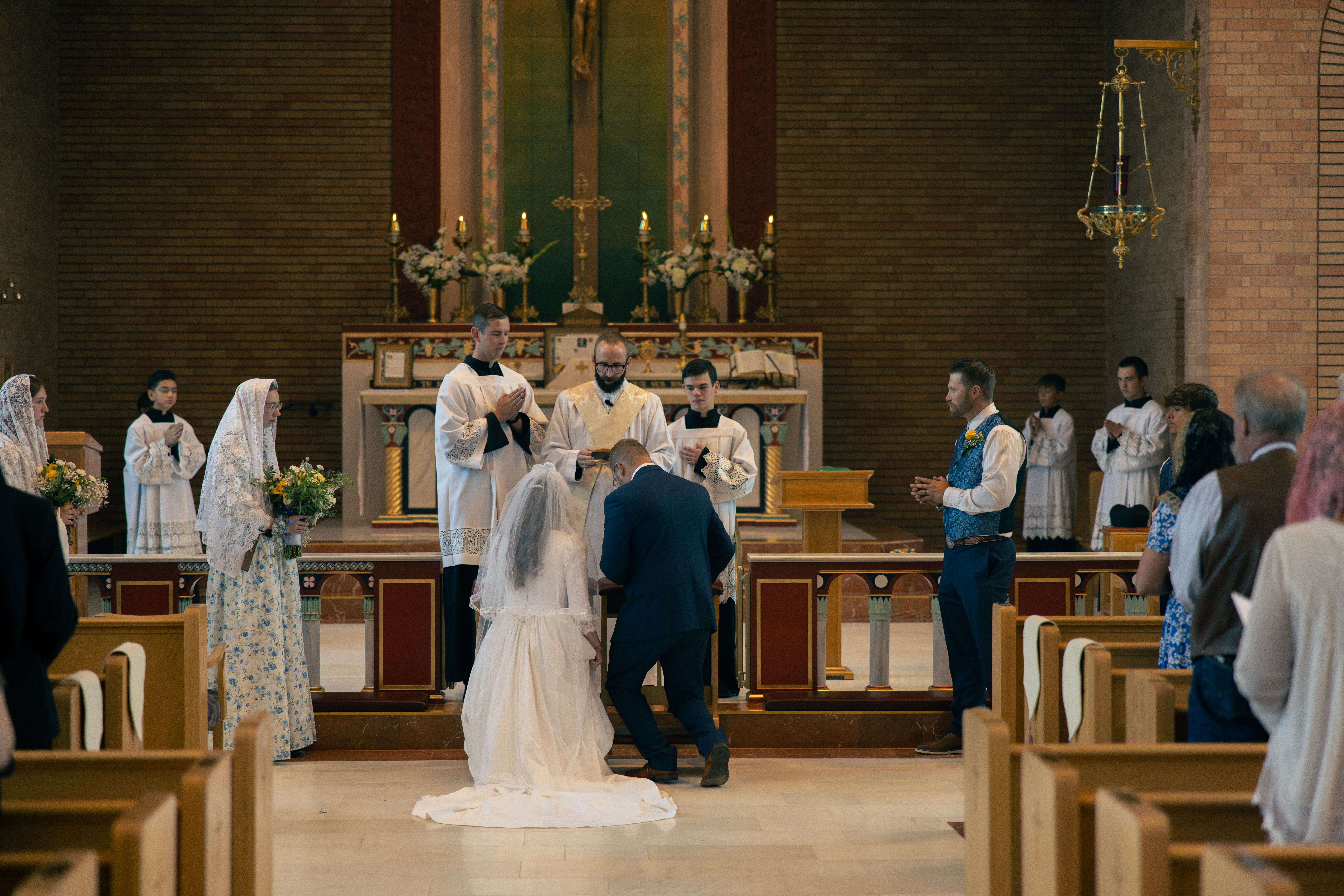 couple kneeling in front of the altar at Corpus Christi Catholic church for their wedding vows