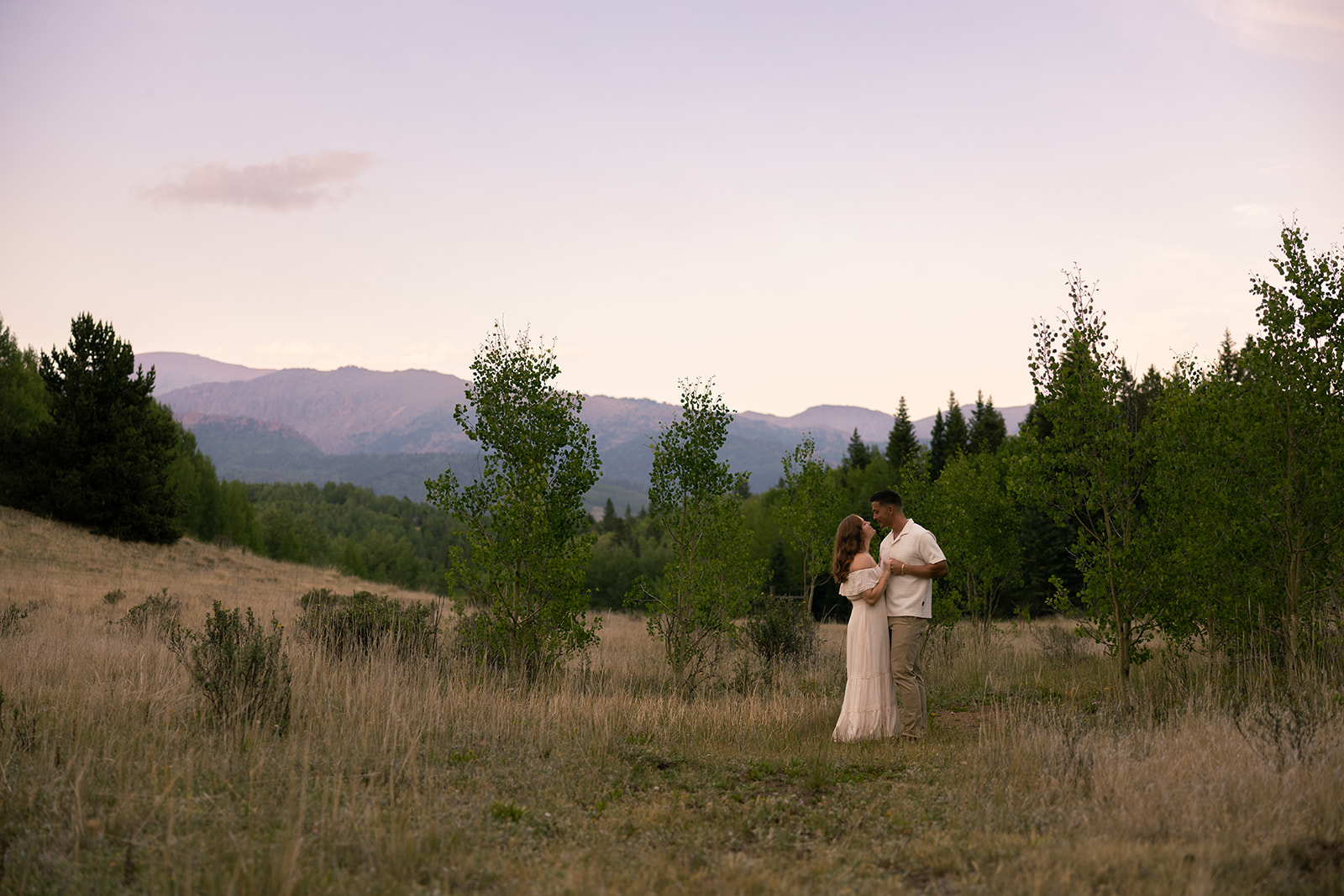 Couple during their engagement session dancing in front of Pikes Peak at sunset (with alpenglow) by colorado wedding photographer alexis dean
